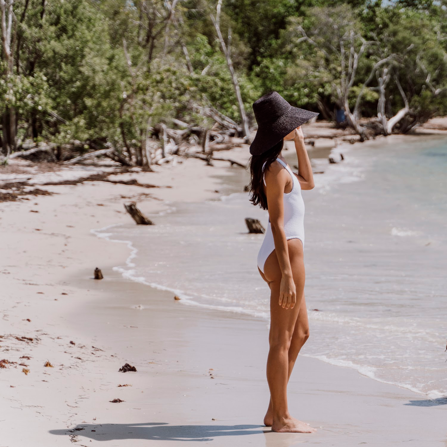 Woman in white swimsuit wearing Verona Extra Wide Brim Packable hat on the beach