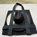 Black woven tote bag with a hat made from natural toquilla straw for stylish versatility