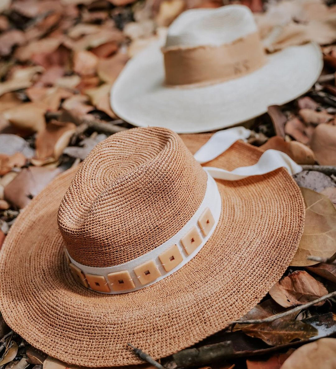 Two stylish toquilla straw hats from Tika featuring custom initials and wide brims