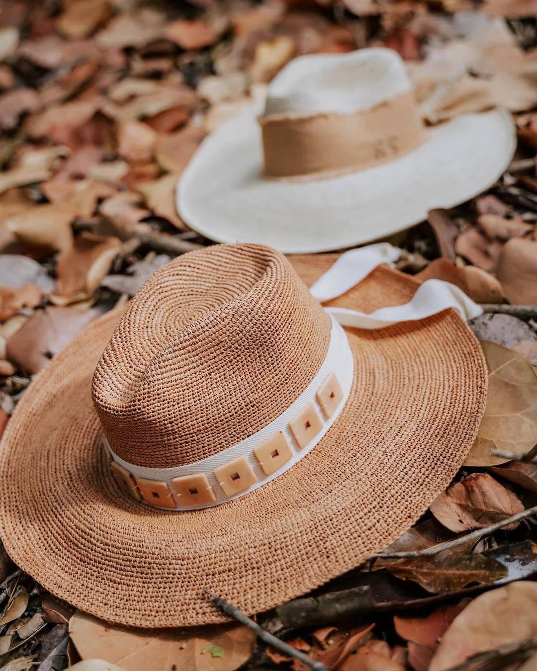 Two stylish toquilla straw hats from Tika featuring custom initials and wide brims