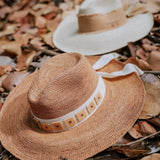 Two stylish toquilla straw hats from Tika featuring custom initials and wide brims
