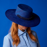 Blue toquilla straw hat with dark trim for sun protection, featuring a wide brim design