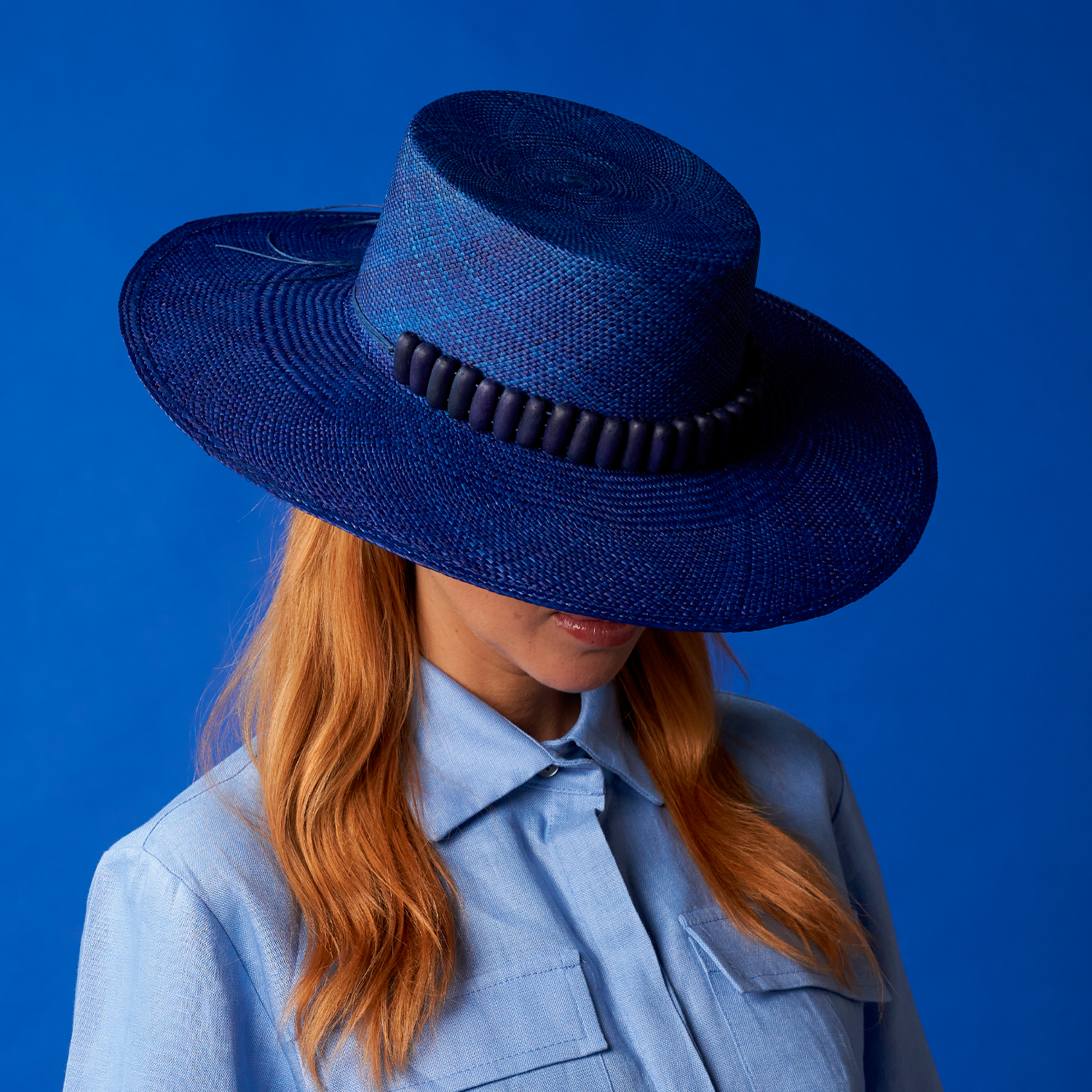 Blue toquilla straw hat with dark trim for sun protection, featuring a wide brim design