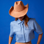 Woman wearing a blue crop top and cowboy hat made from sustainable toquilla straw