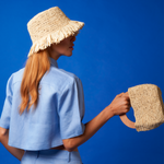 Woman in genuine Panama hat with frayed edges, holding a toquilla straw bag