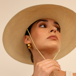 Woman wearing a natural Toquilla straw Panama hat with chin strap as part of Bromelia