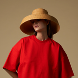 Woman in red shirt and straw hat made of natural mocora straw in Bali