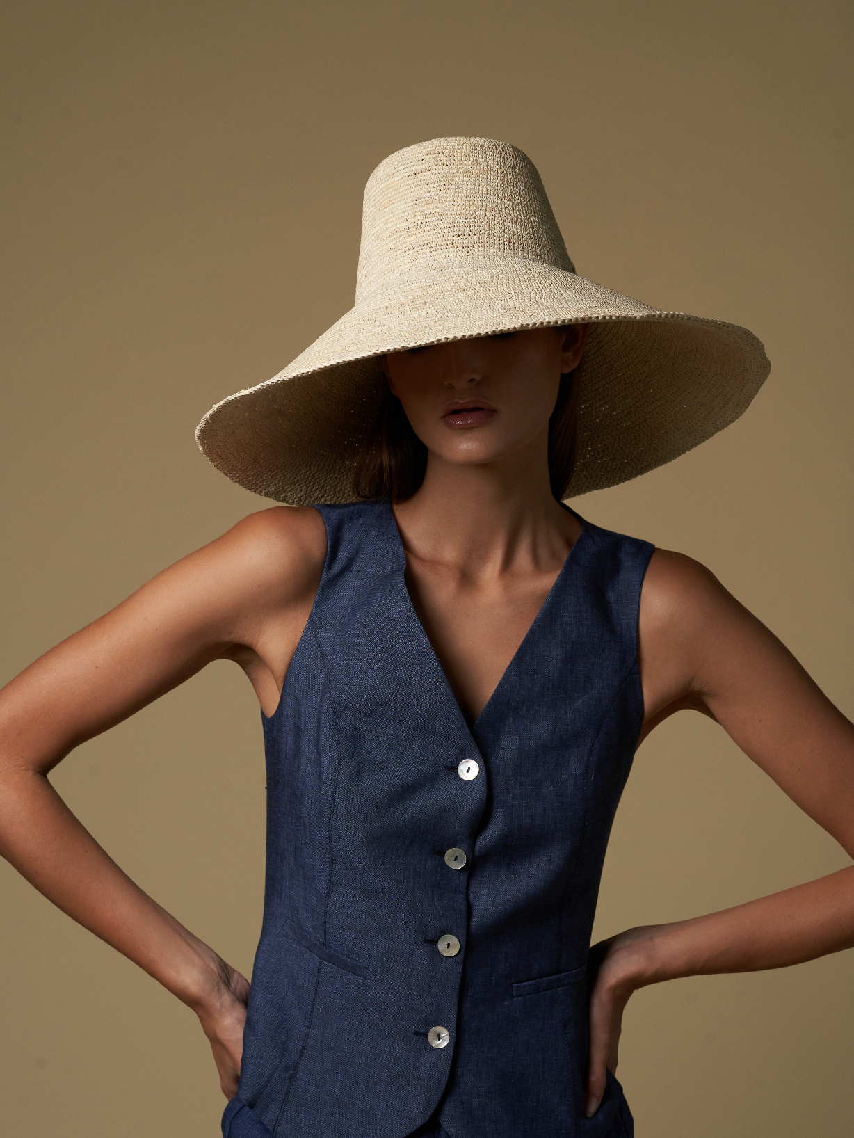 Woman wearing Verona Extra Wide Brim Packable straw hat and navy vest in sunny setting