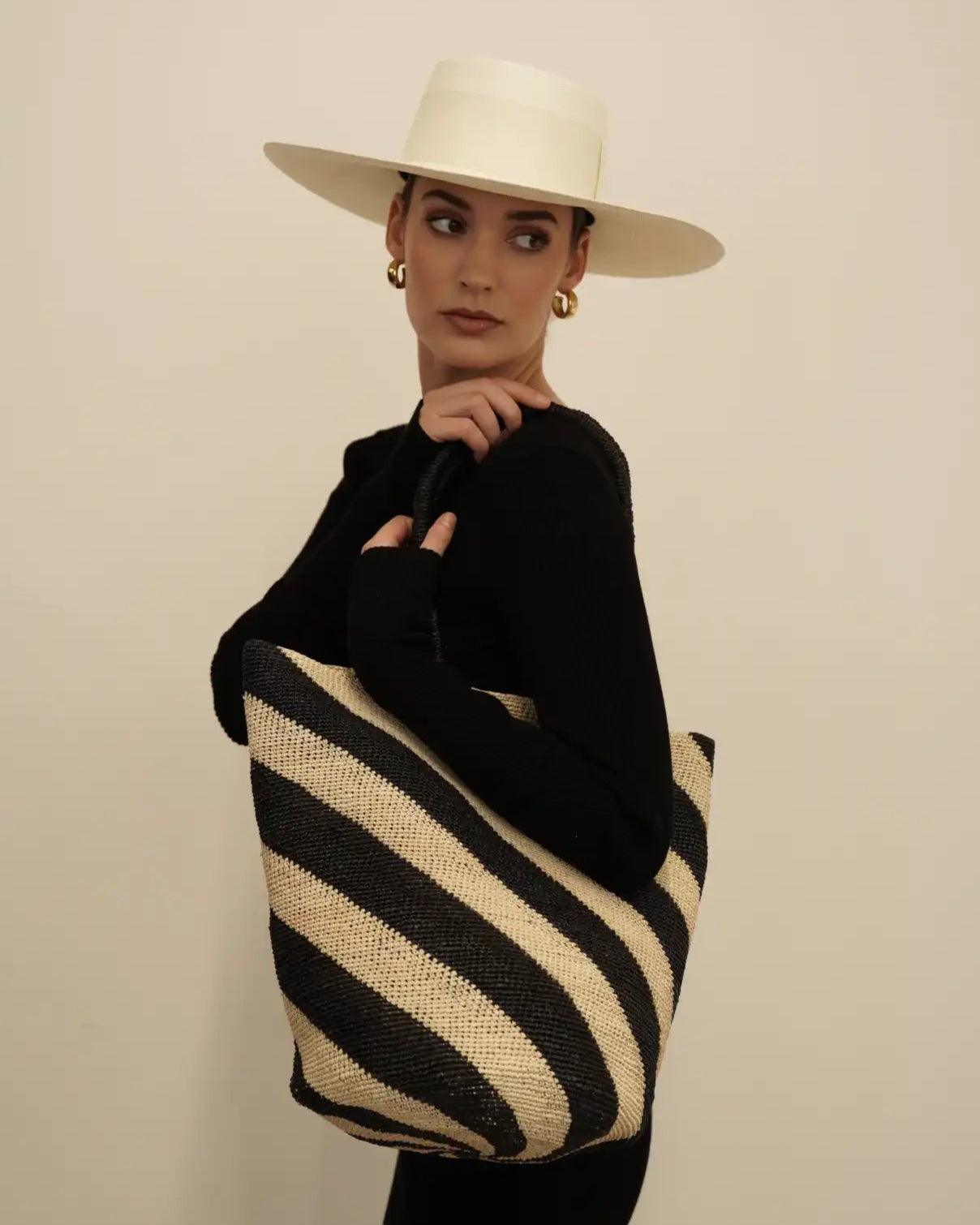 Striped black and cream woven straw tote bag with handles.