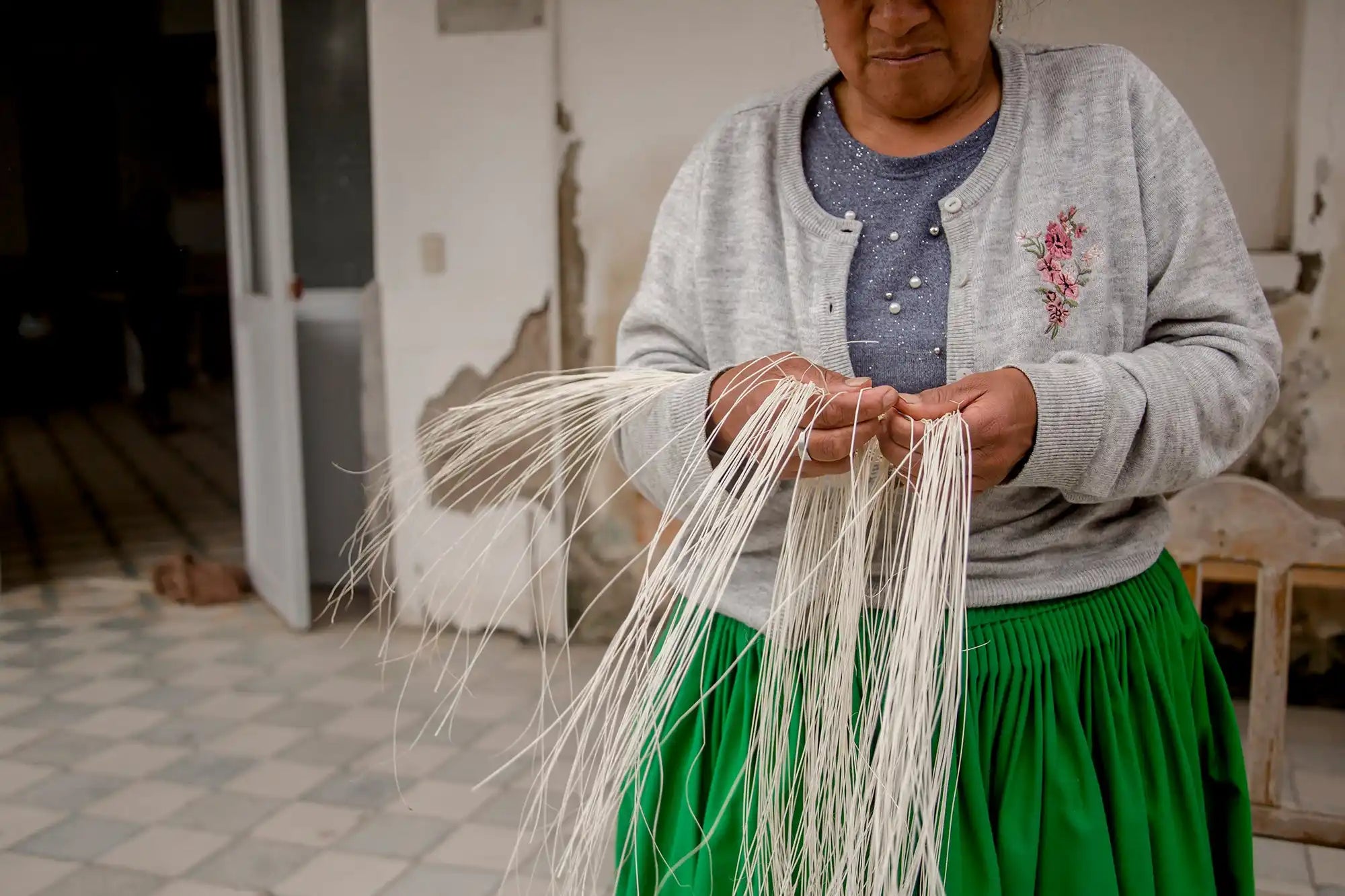 White strands of fiber or thread being held between two hands.